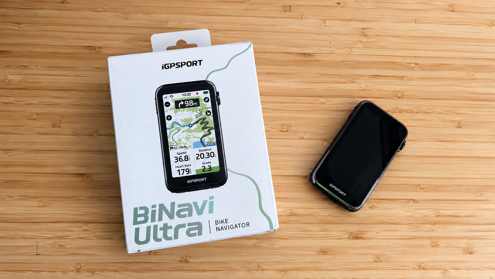 Ciclocomputador GPS iGPSPORT BiNavi Ultra junto a su caja original sobre una superficie de madera